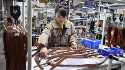 3月28日在中国安徽省阜阳市，为汽车市场供应汽车配件的工厂员工们在线束生产线上工作。（图取自法新社）
