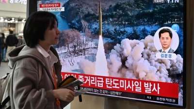 在韩国首尔一火车站，一名女子周二走过电视屏幕上播放有关朝鲜当天向东部海域发射弹道导弹的相关新闻报导。（图取自法新社）