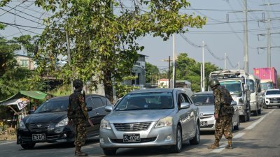 缅甸安全部队成员上周二在仰光的道路上检查来往汽车。（图取自法新社）