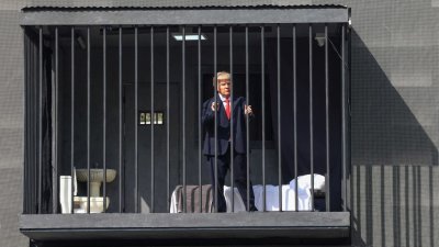 周三在德黑兰塔吉里什广场，一名戴著美国总统特朗普面具的伊朗演员出现在一个模拟监狱牢房内，该牢房被安装在街头广告看板上。（图取自法新社）