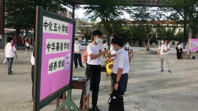 麻坡中化中学周六举行新生入学试，考生在进入考场前量体温。