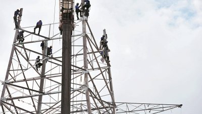 高高的电塔上站著一些工作人员，个个全副武装，这是一份高危的工作，安全措施一定要做好。