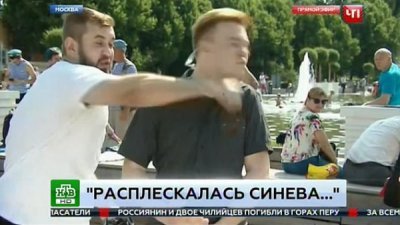 俄罗斯记者现场直播伞兵节庆典时遭到一名醉汉乱入直播现场。醉汉朝记者脸上出拳，记者表情痛苦。