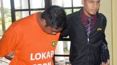 身穿橘色反贪会扣留衣的其中一名被告莫哈末依鲁万（左）在反贪会官员押送下抵达法庭，全程低头避开媒体镜头。