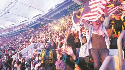 观赏东运会开幕礼的出席者情绪高昂挥动著国旗，喝彩声充满整个武吉加里尔体育馆。（摄影：张真甄）