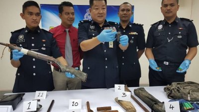 吕连来（中）展示嫌犯私藏的旧式手榴弹，而桌上的则是警方起获的毒品及其他枪械等。左起为祖基菲、莫哈末查基、努鲁哈迪及阿末利端。