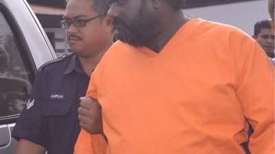 身著橙色囚衣的沙西古玛（右）被警方带往金宝推事庭面控。