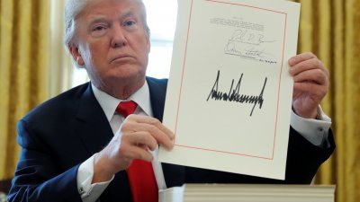 特朗普周五在白宫椭圆形办公室，签署价值1兆5000万美元税收改革计划后，向传媒展示他的签名。