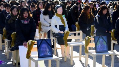 韩国首尔周三举行的纪念“慰安妇”活动，清一色女性围坐著“慰安妇”雕像（中）进行哀悼，前排椅子上则摆放著8名于今年离世的慰安妇人头像。