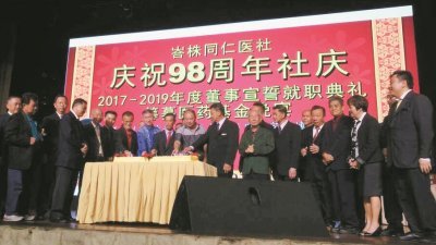 峇株同仁医社全体理事一同切蛋糕，庆祝成立98周年纪念。前排左6起为江明光、叶世忠及杨叔兴。