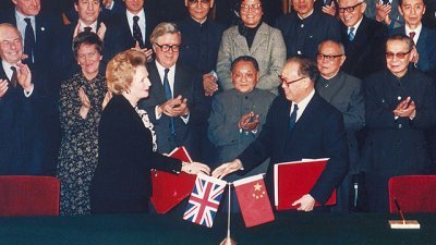 1984年12月19日，英国首相撒切尔夫人（前左）与中国总理赵紫阳（前右）签署《中英联合声明》，邓小平（中）在场见证。 