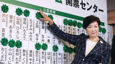 东京都知事小池百合子领导的政党“都民第一之会”在周日都议会选举中，成功登上第一大党地位。图为她为党内胜选者标上记号。