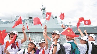 航母编队的导弹驱逐舰“银川”号抵达昂船洲军营时，在码头列队迎接的学生们，高兴挥舞中国五星红旗和香港区旗。