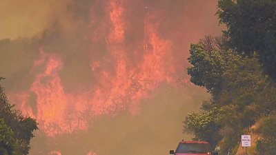 加州南部圣巴巴拉山火，仅5%获得控制，一辆汽车在遭山火包围的高速公路上缓慢行驶。