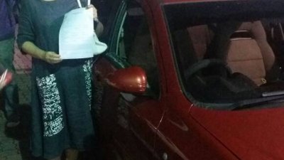 玛丽亚陈向媒体展示报案书和被硬物击碎车窗的轿车。