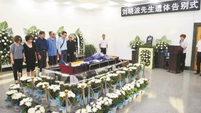 刘晓波的告别式在沈阳市南郊的浑南区殡仪馆举行，刘晓波的遗体摆放在告别厅中央，四周簇拥著素色的花，刘霞（左6）等6名家属站在棺木旁。