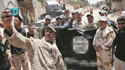 伊拉克政府军成功收复摩苏尔，对IS组织而言是一大挫败。图为伊拉克士兵拿著IS的旗帜拍照，庆祝胜利。