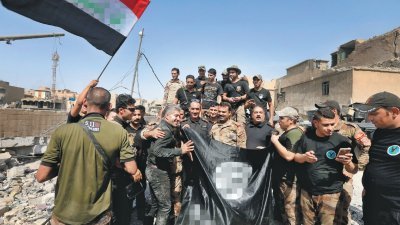 伊拉克政府军本月初收复摩苏尔，特种作战部队 拿著一面被遗留的IS旗帜，庆祝胜利。