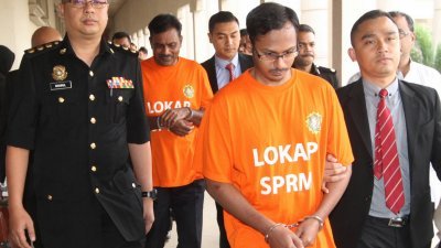 国大党前副主席峇拉克里斯南（左2）与儿子（左3）因涉贪，周三被反贪会官员带往吉隆坡地庭面控时，神色沉重。（摄影：伍信隆 ）