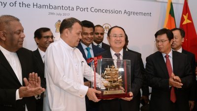 斯里兰卡港口运输部部长萨马拉辛哈（ 左） 和中国招商局集团副总经理胡建华（右），在签署汉班托塔港特许经营协议后，互赠纪念品。