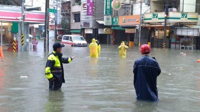 受台风影响，屏东沿海地区周六降豪雨，沿海乡镇淹水。图为警员在淹水地区指挥交通。