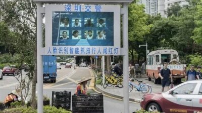 《华尔街日报》近日刊登深圳人脸识别智能抓交通违规的例子：如果有行人闯红灯，会被监控摄像头自动抓拍并实时显示在电子屏上。