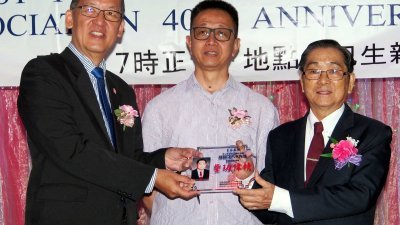 方志民（左）颁发服务奖予在巴生滨海杂货商零售商公会服务40年的陈朝正，中为邓章钦。