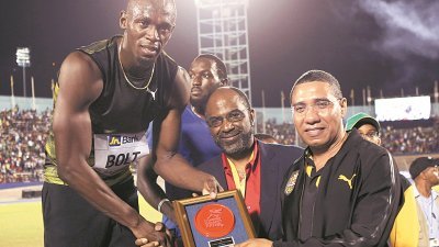 牙买加短跑飞人“闪电”博尔特，从牙买加总理霍恩斯（右）手中，接过了纪念奖座；中为牙买加国家建设银行总经理贾雷。