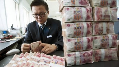 报告指出，中国私人财富市场高速增长，千万富豪人数暴增。这是中国建设银行的员工，在计算100元人民币钞票。