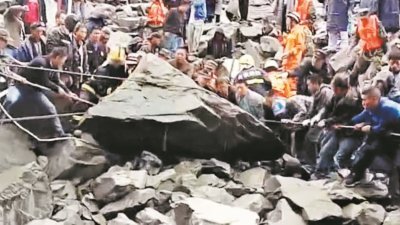 救援队伍发现石堆下疑似有生命迹象，救援人员利用绳索，在民众的协助下试图搬动石块。