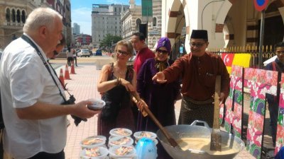 尤再迪（右）邀请来自波兰的游客一起烹煮榴梿甜糕，体验制作传统甜糕的乐趣。