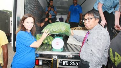 扎哈鲁丁（右）协助苏扎娜把吉隆坡批发公市多出的蔬菜和水果搬上罗里，以捐给慈善机构。