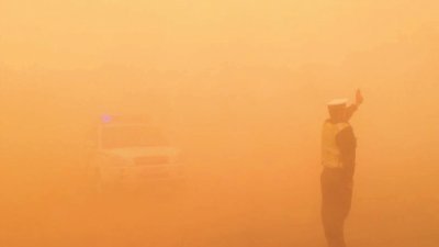 内蒙古自治区遭遇沙尘暴天气，空气发黄混浊，能见度降低，气温下降。沙尘中，阿拉善右旗的交通警察仍坚守戈壁路，指挥交通。