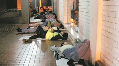 大马客工清晨越堤到新加坡，趁上班前躺在便利商店门口补眠。