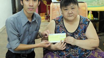 本报记者李文艺（左）移交本报读者捐助的9515令吉 善款予曹日兰。