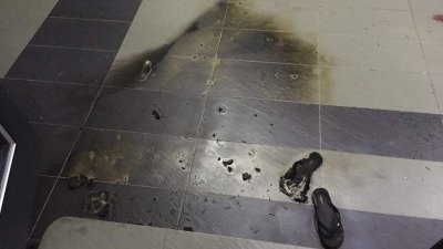 林德和住家遭人抛汽油弹后，地面乌黑一片，一双拖鞋子被烧毁。