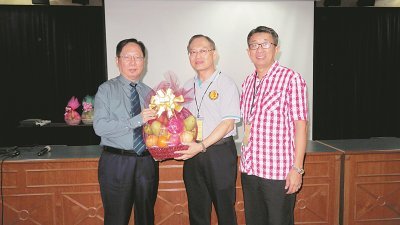 张贤炳（中）赠送水果礼篮予刘利民（左）。右为署理主席吴小铭。