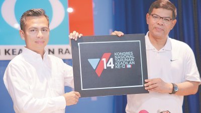 赛夫丁（右）展示第12届公正党代表大会的标志，“V”字符标志著在第14届大选的胜利。左为法米。