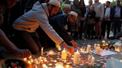 数名穆斯林男子周三在曼彻斯特市中心举行的祈福活动上，点燃蜡烛哀悼恐袭遇难者。