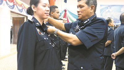 阿斯里（右）为一名华裔女警官吴慧仪（左）挂上助理警监的警勋。