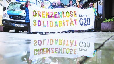  二十国集团财长会议周六在德国巴登-巴登举行，示威者在会议场外拉布条示威，布条上写著：“团结无疆界，取代G20”。
