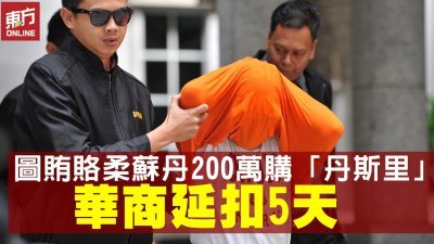 华裔丹斯里周五被反贪会官员带上布城推事庭申请延扣时，用橙色外衣遮住头部，避开媒体的镜头。
