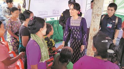 因罗兴亚人危机饱受国际批评的昂山淑姬（中）周四到访若开邦北部的孟都，与当地缅族人民会面，热情握手闲话家常。