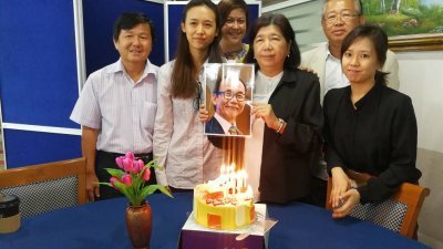 刘秀玉（右3）、许思恩（左2）与家人带著许景城的照片，为他庆祝63岁生日。