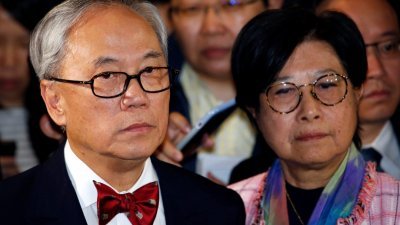香港前特首曾荫权（左）上周五在夫人的陪同下，离开高等法院，被媒体包围追访。