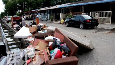 灾民重返家园，把损坏 的家具移到户外，形成 一个大型垃圾堆。（摄影：何湘芸）