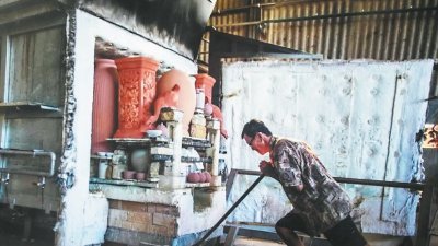 陶瓷制作过程繁琐，图为郑文华将载满陶器的窑车推进气窑内烧制。