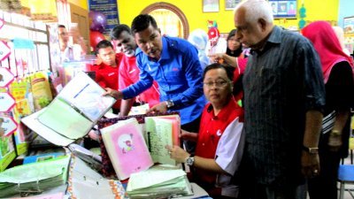 依斯迈沙比里（中）在槟巫统主席拿督慕沙（右）和再迪陪 同下，在峇东埔柏玛当拉哇幼儿园检视受水灾损坏的书籍。