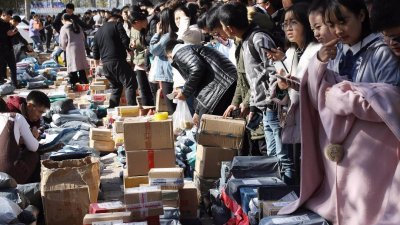参与双11购物狂欢的大学生，在山东省滨州市一所高校校园内排队领取包裹，摆在路上的包裹让人看了眼花缭乱，现场有如大市集。
