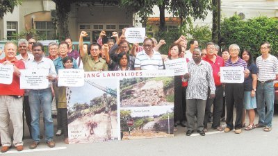郑联语（左4起）及美纳西等人举起大字报及横幅，要求槟州政府解决水灾及土崩等问题。